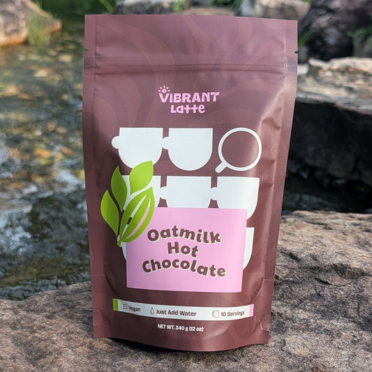 Vibrant Latte oatmilk hot chocolate package on a rock with a natural background
